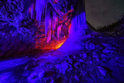 Frozen Waterfall Ice Cave with Colored Lights at Night - Cavern with large frozen ice waterfall popular for ice climbing. Rifle, Colorado USA.