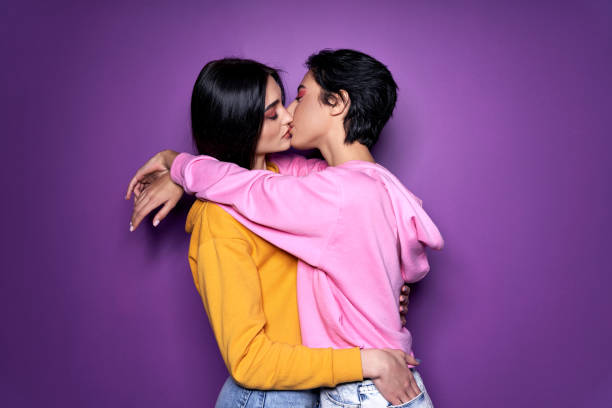 two pretty sexy stylish cool generation z girls lgbtq lesbian couple dating in love hugging enjoying intimate tender sensual moment together kissing with eyes closed isolated on purple background. - sexual activity couple sensuality heat imagens e fotografias de stock