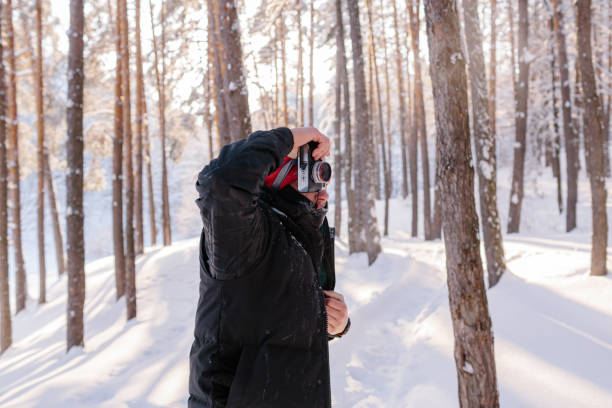 istock Young man takes photos in winter forest 1297260558