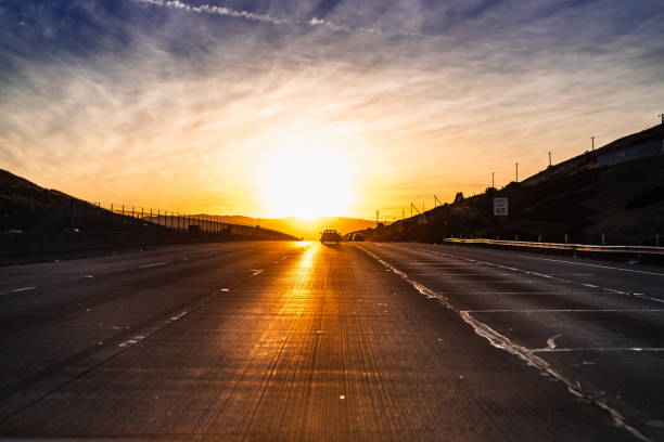 Sunset landscape with bright sunlight just above the horizon, reflecting on the freeway; East San Francisco bay area, California