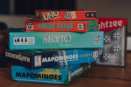 Combe St Nicholas, UK - July 25, 2020: Stack of modern and classing board games on a table. Sales of board games skyrocketed during the Coronavirus pandemic-related lockdowns.