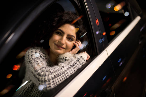 istock Happy woman looking out through car window at night 1297265542