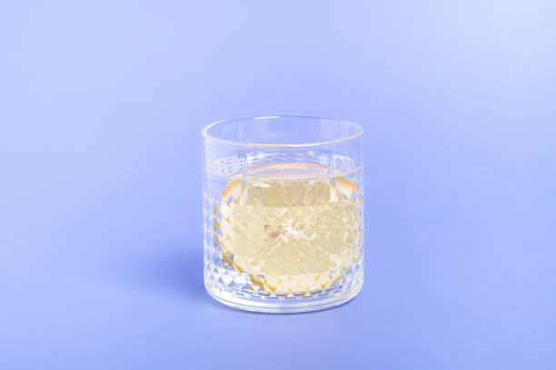 istock Glass with water and lemon on blue background 1297267346