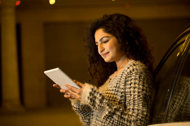 istock Happy woman using digital tablet outdoors at night 1297268307