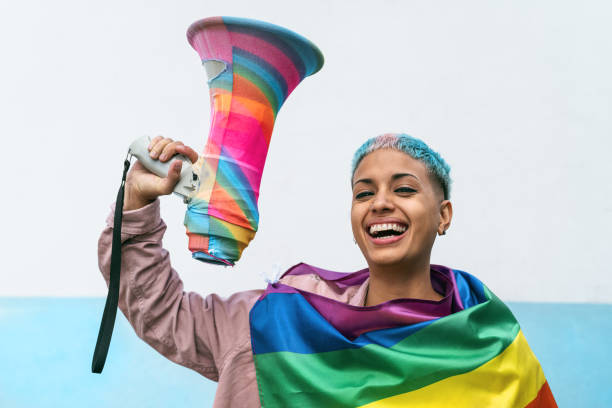 Young woman celebrating gay pride event wearing rainbow flag symbol of Lgbt social movement Young woman celebrating gay pride event wearing rainbow flag symbol of Lgbt social movement social awareness symbol audio stock pictures, royalty-free photos & images