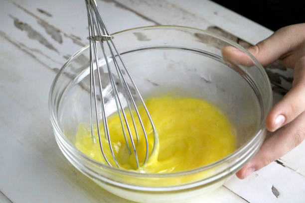 istock Beating Eggs with a Wire Whisk in a Glass Bowl Close-Up 1297268927