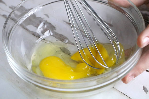 istock Beating Eggs with a Wire Whisk in a Glass Bowl Close-Up 1297269082