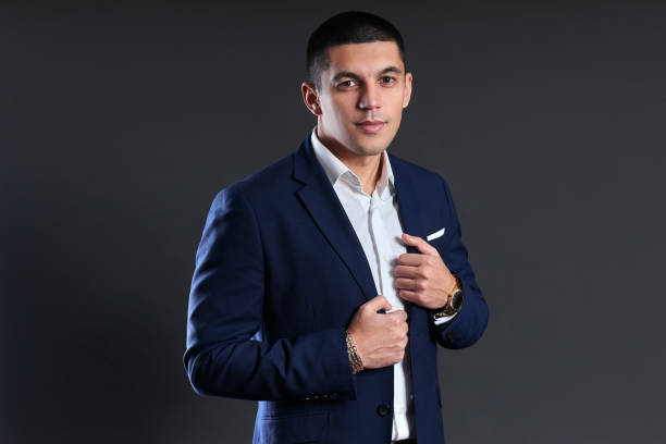 istock Portrait of a businessman in blue jacket on dark background in studio. a man with short haircut. Young confident manager smiles 1297270691