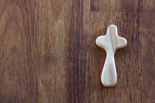 Simple Light wood cross on dark wood background with copy space