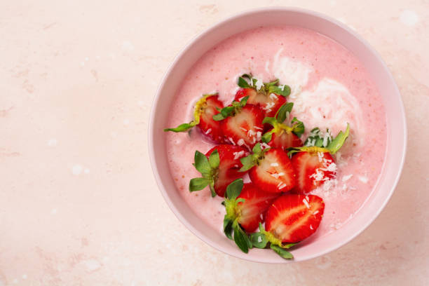 istock Breakfast with granola, coconut and strawberry smoothie in a bowl on a pink light background. Spring diet menu.Top view. 1297272932