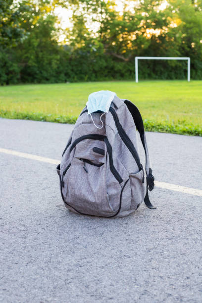 istock School backpack with face mask on the road near school building. 1297274404