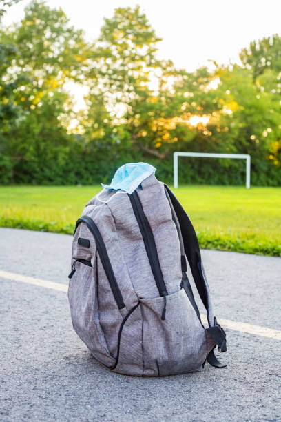 istock School backpack with face mask on the road near school building. 1297274408