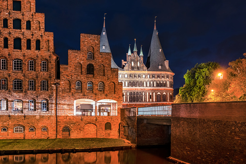Trave shore at night with salt storage and Holstentor in Lübeck, Germany