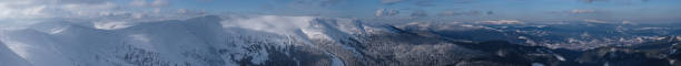 Snow and wind formed ice formations covered winter mountain plateau, tops with snow cornices in far. Magnificent sunny day on picturesque beautiful alpine ridge.