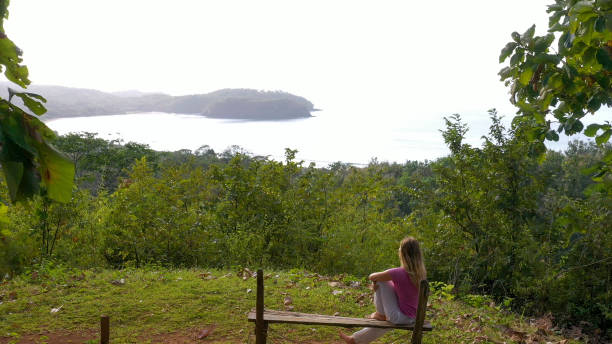 istock Young woman relaxes at coastal viewpoint in the morning 1297277559