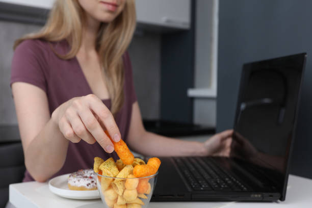 istock Woman working on computer and eating fast food and snacks. Unhealthy Lifestyle 1297277776