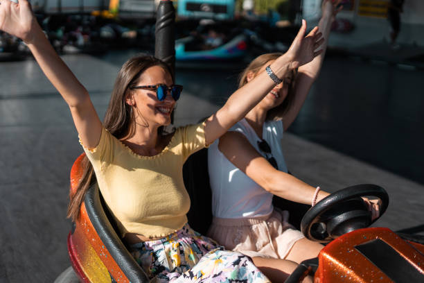 istock Two women having fun in electric bumper car in amusement park 1297278320