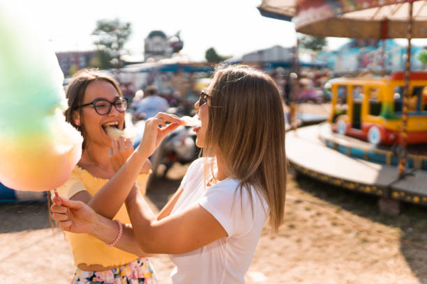 istock Two women spending time in amusement park and eating cotton candy 1297278340