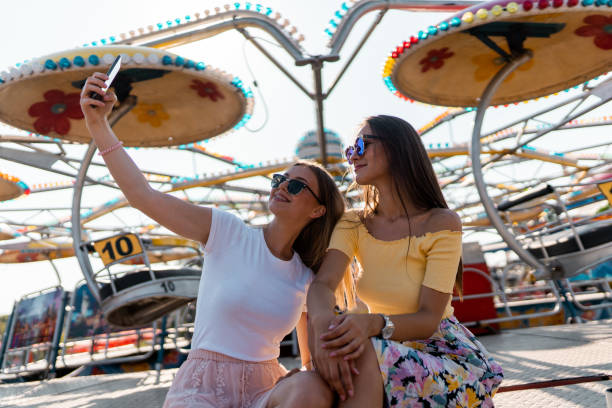 istock Two young women spending time in amusement park and taking selfie 1297278357
