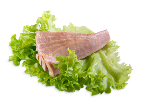 Tuna slices isolated on white background close up with green lettuce stock photo