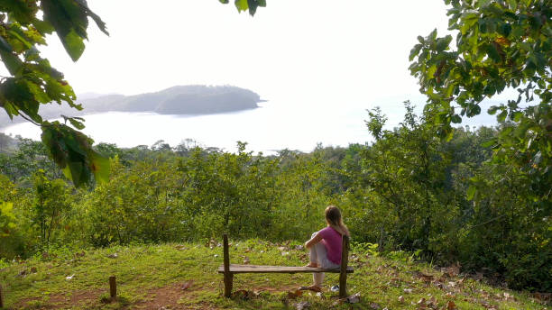 istock Young woman relaxes at coastal viewpoint in the morning 1297278517