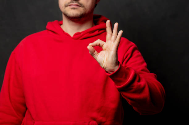 istock White guy in red sweatshirt show OK gesture on dark background 1297280434