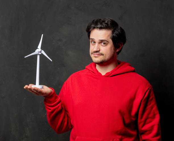istock guy in red sweatshirt hold little wind generator on dark background 1297281024