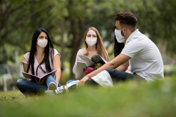 istock University students studying together outdoors and wearing facemasks during the COVID-19 pandemic 1297281074