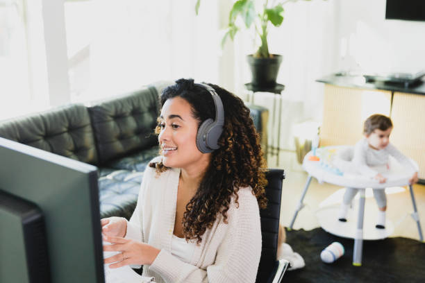 istock While baby plays in background, woman meets virtually with coworkers 1297281367