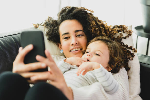 istock Mother and boy lie on sofa to take selfie 1297281393