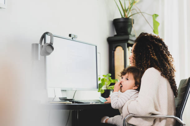 istock Mom holds her baby while telecommuting 1297281444