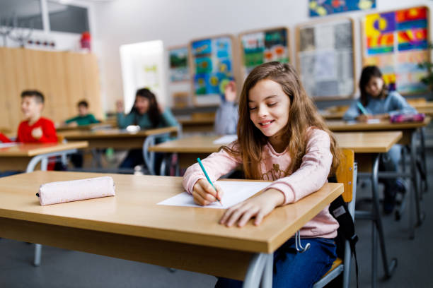 istock Happy schoolgirl writing a dictation on a class in the classroom 1297282924