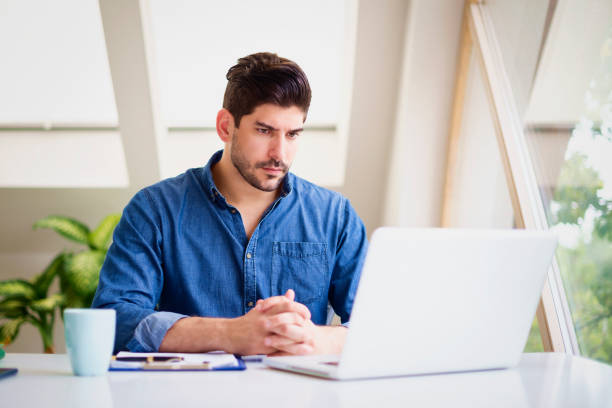 istock Businessman looking thoughtfully while working on laptop at home 1297282978