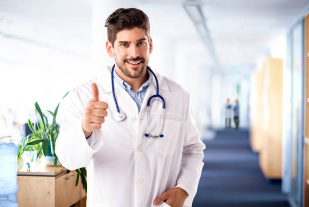 istock Happy male doctor giving thumbs up while looking at camera and smiling 1297282984