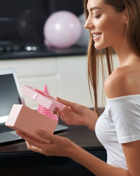 istock Young woman unpacking present video call at home 1297284191