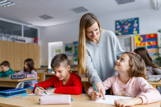 istock Happy elementary teacher talking to kids in the classroom 1297284537