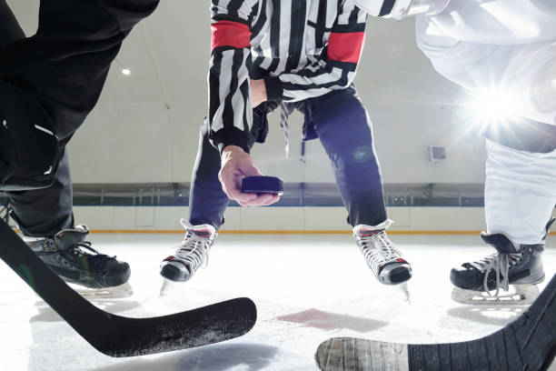 istock Hockey referee with puck standing on ice rink between two players with sticks 1297286038