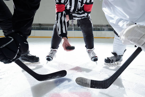 istock Hockey referee with puck standing on rink with two rivals on his right and left 1297286042