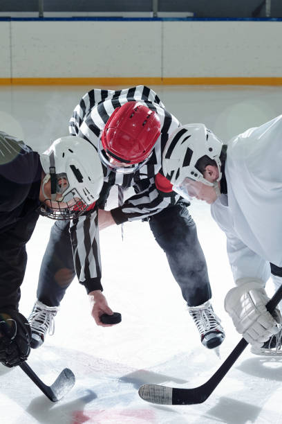 istock Hockey referee with puck and rivals with sticks standing on his right and left 1297286065