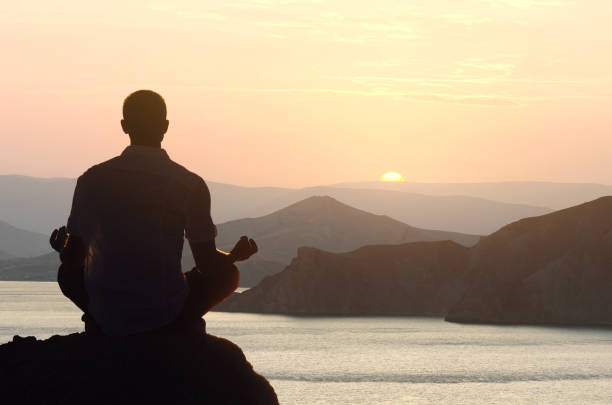 istock Man meditates at dawn in the lotus position 1297288603