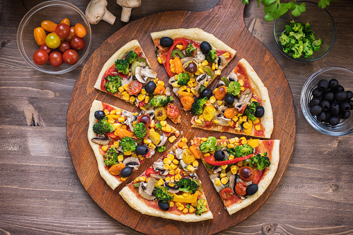 Homemade vegetarian pizza with broccoli, cherry tomato, pepper, black olives and mushrooms