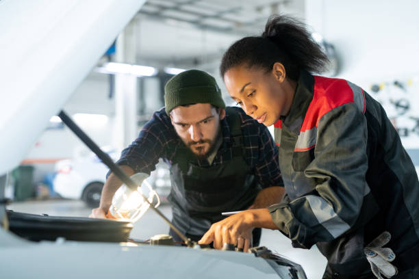 istock Young bearded man in workwear holding lamp and bending over open hood 1297291371