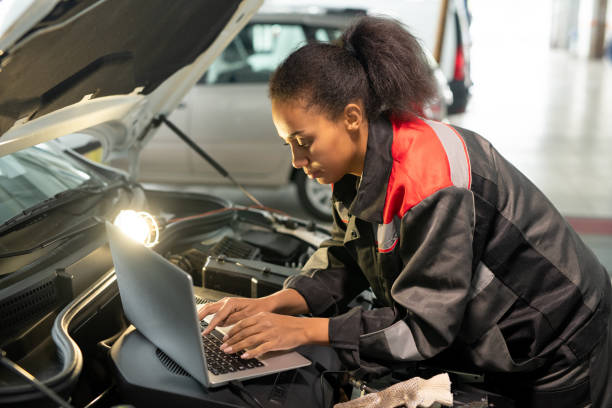 istock Female worker of car repair service using laptop over open engine compartment 1297291901