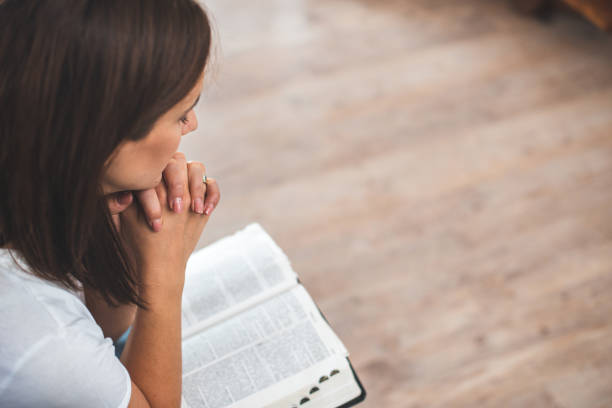 young woman pray with bible relationship with God at home stock photo