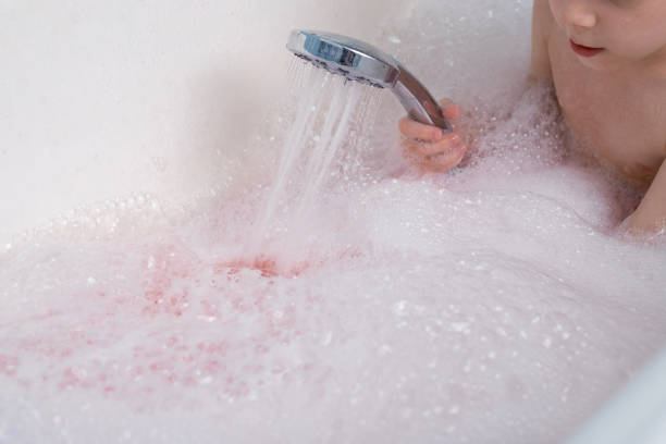 istock The child makes lather in the bath with the shower. Taking a bath, hygiene procedures. 1297293680