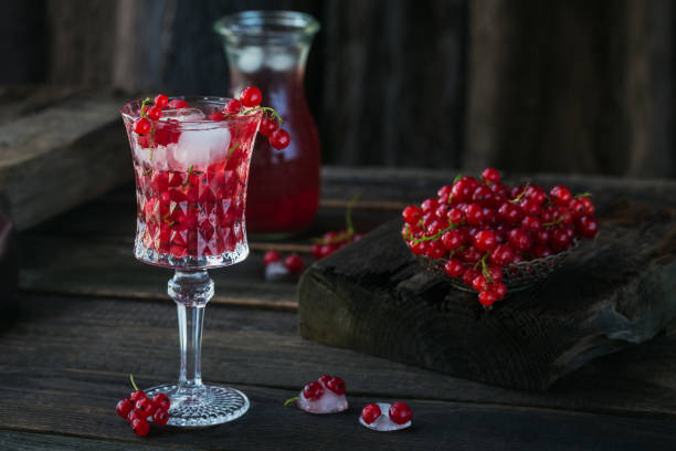 summer drink with white sparkling wine. homemade refreshing fruit cocktail or punch with champagne, red currant, ice cubes and mint leaves on a dark wooden background - ice cube cold mint punch imagens e fotografias de stock
