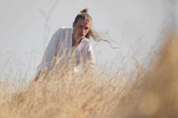 istock A boy with long hair and dressed in white models in a natural park 1297294672