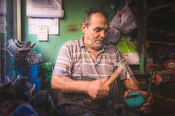 An environmental portrait of a local Turkish cobbler repairing a shoe from his workshop in the Istanbul neighbourhood of Balat.