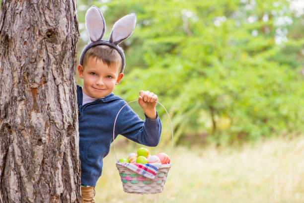 szczęśliwe dziecko wygląda z drzewa gospodarstwa kosz pełen kolorowych pisanek po polowaniu na jajka na wiosnę. wesołych świąt. - costume expressing positivity cheerful close up zdjęcia i obrazy z banku zdjęć
