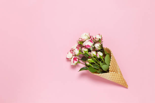 istock Small roses in waffle cone on pink background, copy space. Minimal style flat lay. For greeting card, invitation. March 8, February 14, birthday, Valentine's, Mother's, Women's day concept. Top view 1297301253